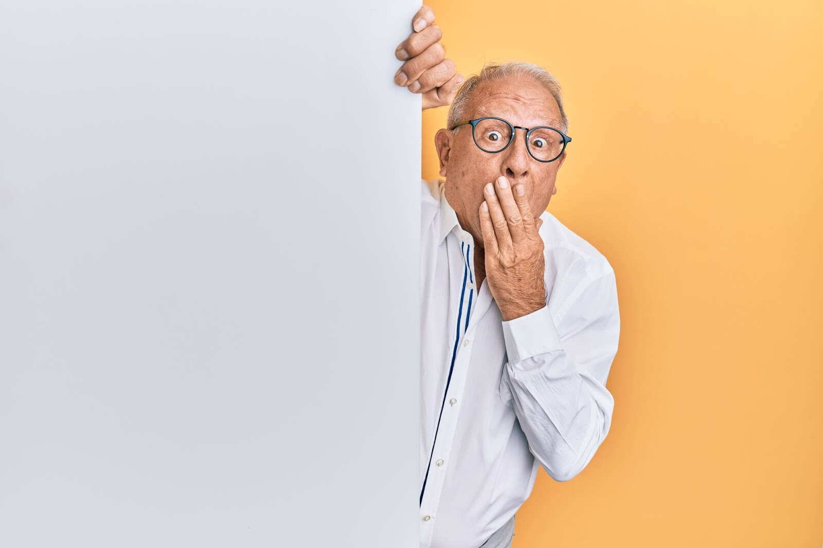 a male senior covering his mouth with one hand in shock