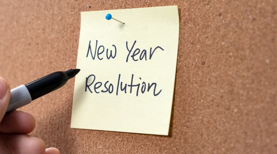 Image of someone writing New Year Resolution on a sticky note